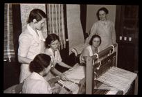 Group of women at a loom. Black and white photo. 
